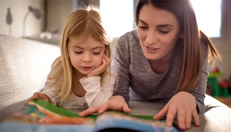 Mère qui lit un livre avec sa fille de primaire
