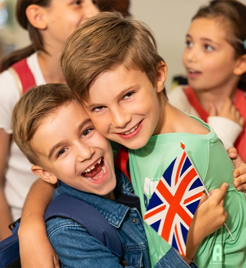 Deux élèves de primaire heureux qui tiennent un drapeau anglais avec Acadomia - photo tous droits réservés