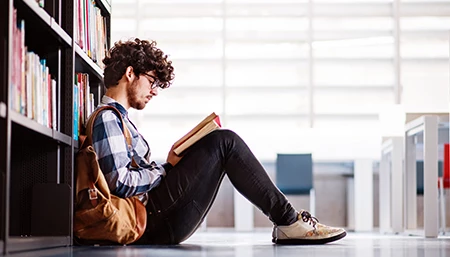 Etudiant qui lit dans une bibliothèque