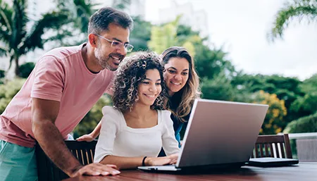 Parents avec leur fille qui regardent un ordinateur