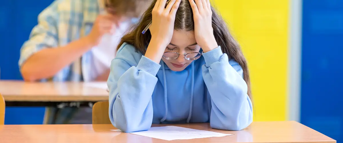 Jeune élève découragée devant copie d'examen