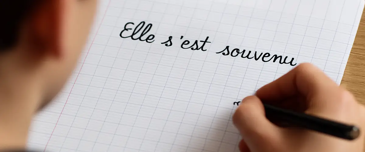 Cahier blanc avec texte écrit dessus "Elle s'est souvenu" - dictée orthographe en cours de français Acadomia