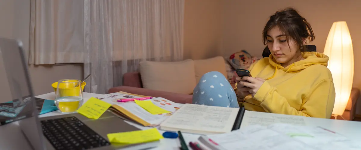 Adolescente sur son téléphone au lieu de travailler ses devoirs - Acadomia