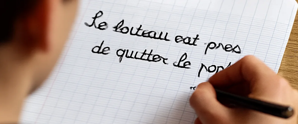 Cahier d'école avec texte "Le bateau est près de quitter le port" - exercice orthographe avec Acadomia