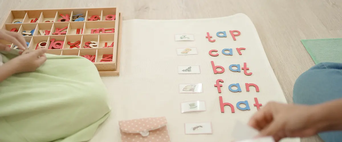 Deux enfants en maternelle apprennent à former des mots simples avec des lettres mobiles Montessori lors d'un atelier de lecture Acadomia