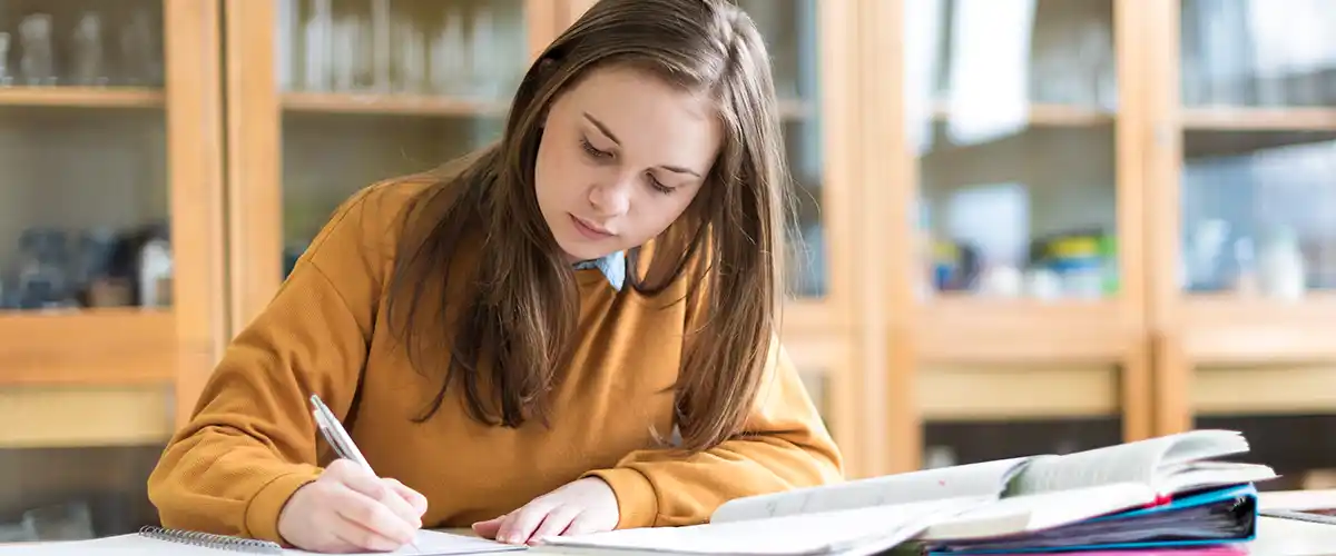 Une lycéenne concentrée prend des notes dans une salle de cours Acadomia