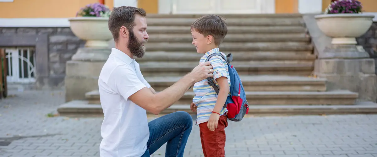 Un père accompagne son fils devant une école pour la rentrée scolaire