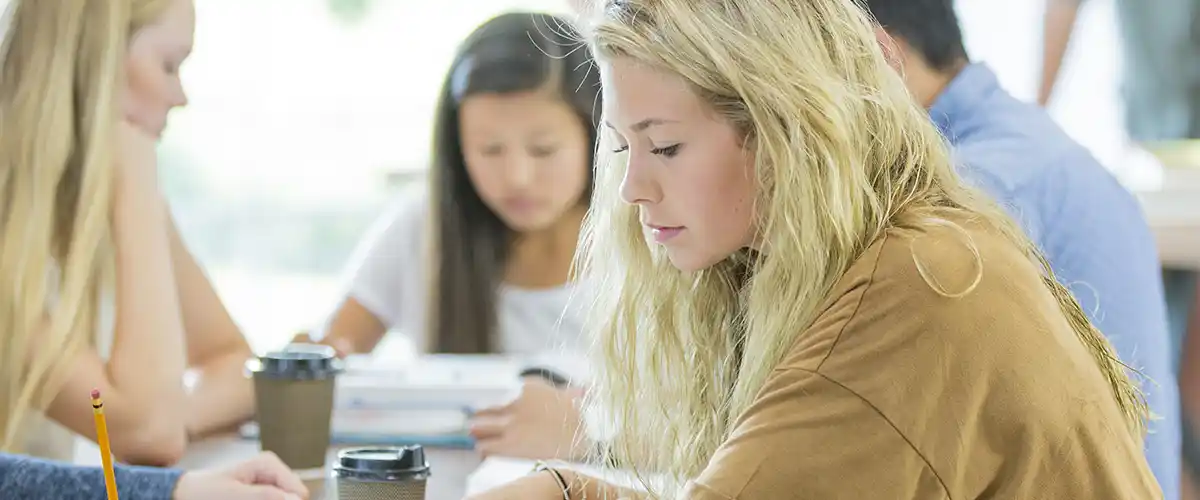 Groupe de lycéennes concentrées travaillant sur leurs exercices dans une salle de cours Acadomia