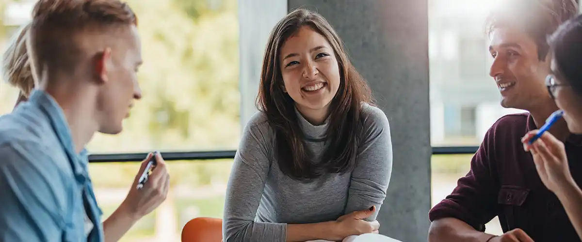 Groupe d'étudiants souriants échangeant dans une salle lumineuse d'un centre Acadomia