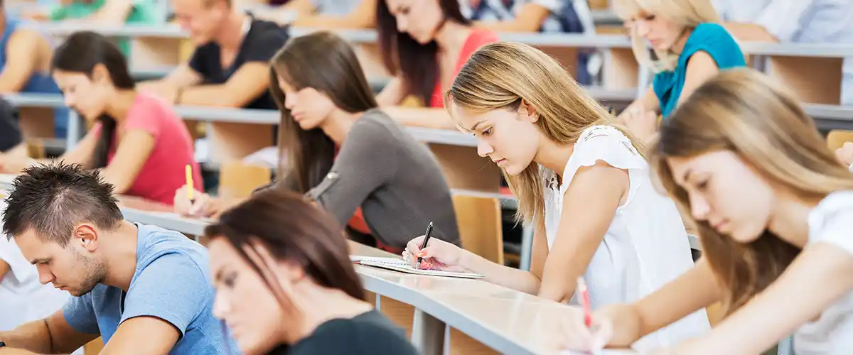Groupe d'étudiants concentrés passant un examen écrit dans un amphithéâtre universitaire