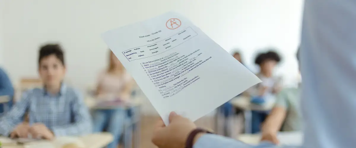 Un élève satisfait découvre son excellent résultat avec un A+ sur sa copie d'examen dans une salle de classe