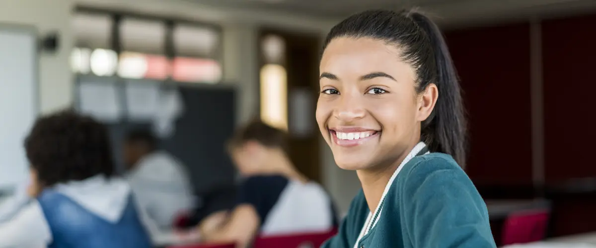 Une lycéenne souriante et épanouie pose avec confiance dans une salle de cours Acadomia