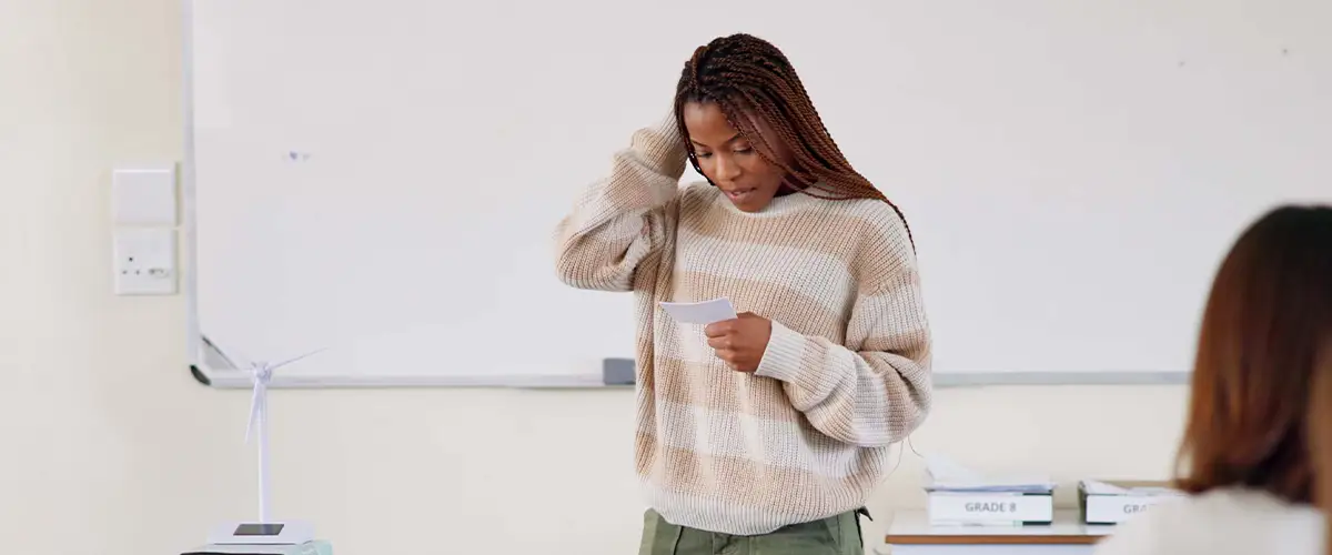 Une lycéenne stressée révise ses notes avant une présentation orale dans une salle de classe Acadomia