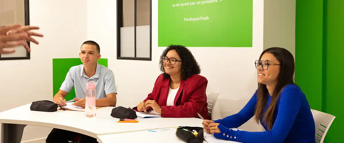Trois étudiants souriants suivent attentivement un cours dans une salle Acadomia - photo tous droits réservés