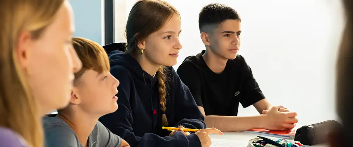 Groupe de collégiens attentifs suivant un cours dans une salle Acadomia
