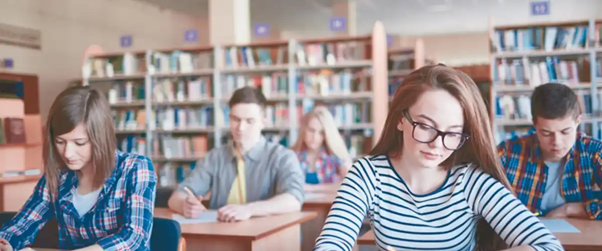 Groupe de lycéens concentrés travaillant sur leurs exercices dans une bibliothèque
