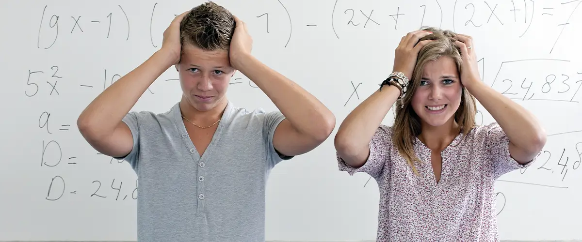 Deux lycéens stressés se tenant la tête devant un tableau de mathématiques dans une salle de cours Acadomia