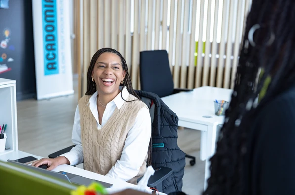 Une collaboratrice Acadomia sourit lors d’un échange dans un espace de travail - photo tous droits réservés
