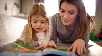 Mère qui lit un livre avec sa fille de primaire