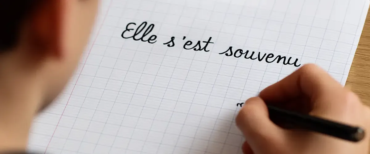 Cahier blanc avec texte écrit dessus "Elle s'est souvenu" - dictée orthographe en cours de français Acadomia
