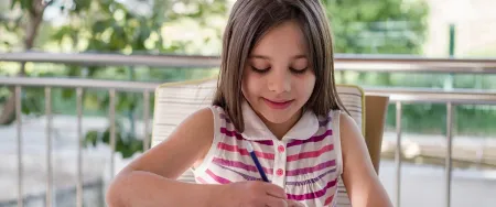 Élève de primaire qui profite de l'été pour réviser des notions mathématiques et français
