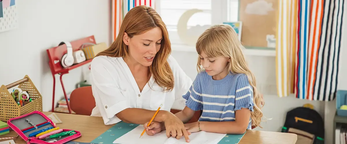 élève de cp effectuant ses devoirs accompagnée de sa mère