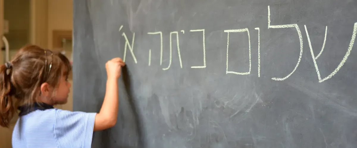 Élève de primaire apprenant à écrire l'hébreu au tableau avec Acadomia