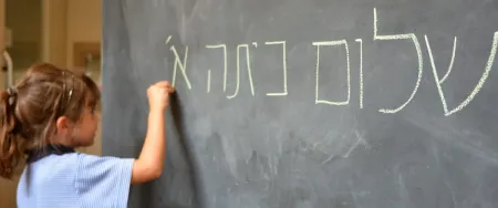 Élève de primaire apprenant à écrire l'hébreu au tableau avec Acadomia