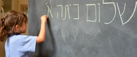 Élève de primaire apprenant à écrire l'hébreu au tableau avec Acadomia