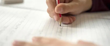 Elève écrit sur un cahier d'école Acadomia