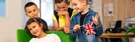 Groupe d'élèves de primaire heureux qui tiennent un drapeau anglais avec Acadomia - photo tous droits réservés