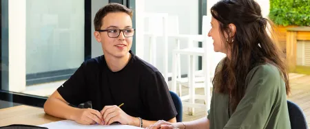 Un collégien souriant échange avec son enseignante Acadomia lors d'une séance de soutien scolaire à domicile - photo tous droits réservés