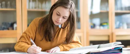 Une lycéenne concentrée prend des notes dans une salle de cours Acadomia