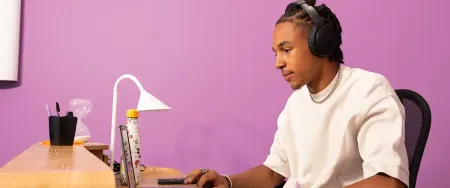 Un lycéen concentré travaille sur son ordinateur portable avec un casque audio dans un espace de travail moderne - photo tous droits réservés