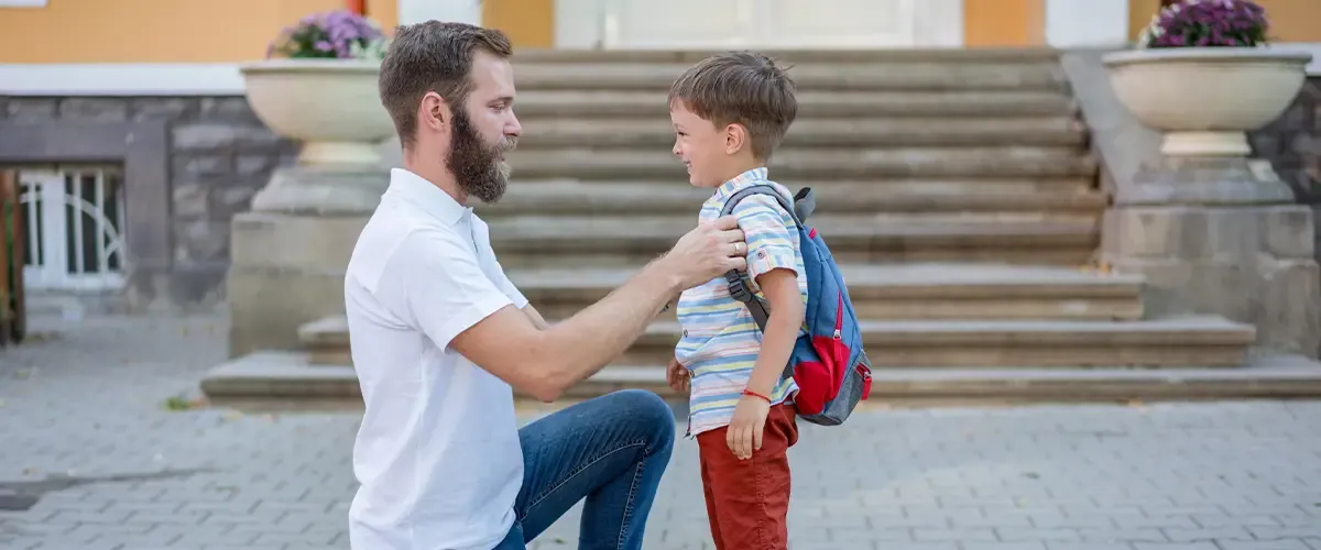 Un père accompagne son fils devant une école pour la rentrée scolaire
