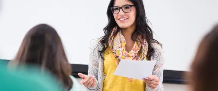 Une enseignante Acadomia souriante présente une leçon à ses élèves dans une salle de cours lumineuse