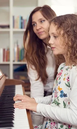 Une professeure de piano Acadomia en cours particulier à domicile avec une jeune élève