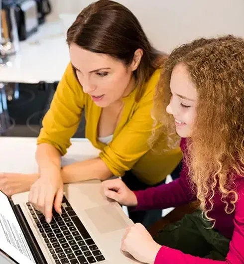 Un parent accompagne son enfant dans son travail scolaire sur un ordinateur portable